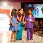A girl cancer patient walks the runway with her registered nurse as she dreams of being an oncologist when she grows up she is participating in the Dream Walk