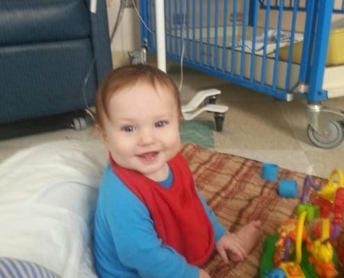 Picture of Jonathan in his hospital rooming smiling and playing with his toys